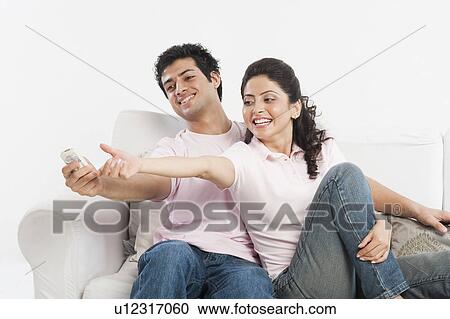 Couple playing with a remote control on a couch View Large Photo Image Stock Image - Couple playing with a remote control on a couch. Fotosearch