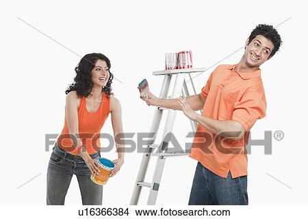 Picture - Couple playing with paints in their house. Fotosearch