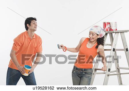 Stock Image - Couple playing with paints in their house. Fotosearch
