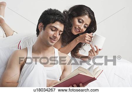 Stock Photo - Couple reading a book in a bedroom. Fotosearch