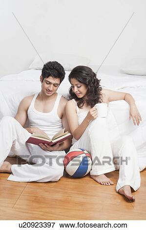 Stock Photo - Couple reading a book in a bedroom. Fotosearch