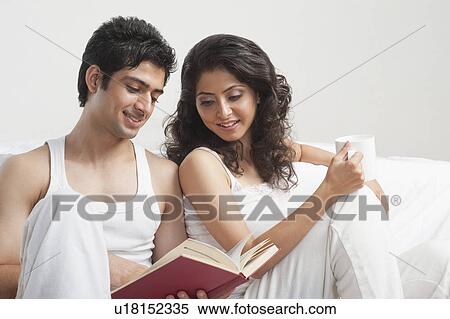 Couple reading a book in a bedroom View Large Photo Image Stock Photography - Couple reading a book in a bedroom. Fotosearch