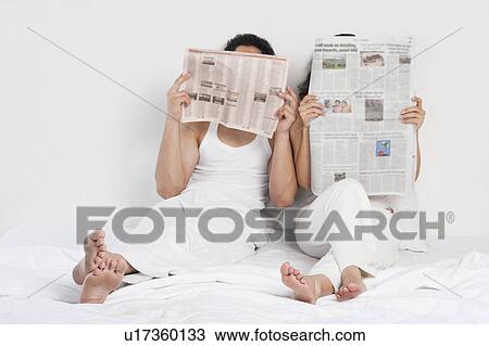Couple reading newspaper on the bed View Large Photo Image Stock Image - Couple reading newspaper on the bed. Fotosearch