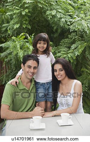 Couple sitting at a table with their daughter View Large Photo Image Stock Image - Couple sitting at a table with their daughter. Fotosearch