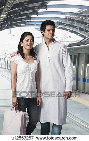 Couple standing at a subway station with a shopping bag View Large Photo Image Stock Photo - Couple standing at a subway station with a shopping bag. Fotosearch