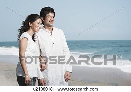 Stock Image - Couple standing on the beach. Fotosearch