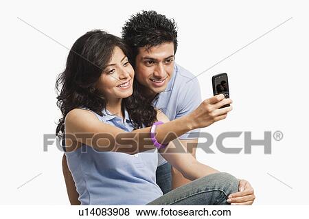 Stock Photo - Couple taking a picture of themselves with a mobile phone. Fotosearch