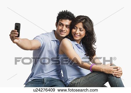 Stock Photo - Couple taking a picture of themselves with a mobile phone. Fotosearch