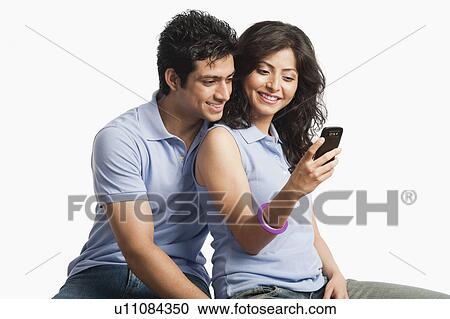 Stock Image - Couple text messaging on a mobile phone. Fotosearch