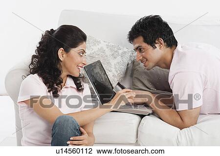 Stock Image - Couple using a laptop and holding a credit card. Fotosearch