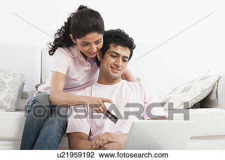 Stock Image - Couple using a laptop and holding a credit card. Fotosearch