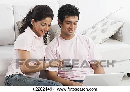 Stock Photo - Couple using a laptop and holding a credit card. Fotosearch