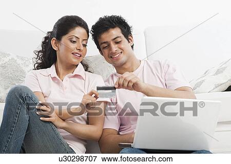 Couple using a laptop and holding a credit card View Large Photo Image Stock Photo - Couple using a laptop and holding a credit card. Fotosearch
