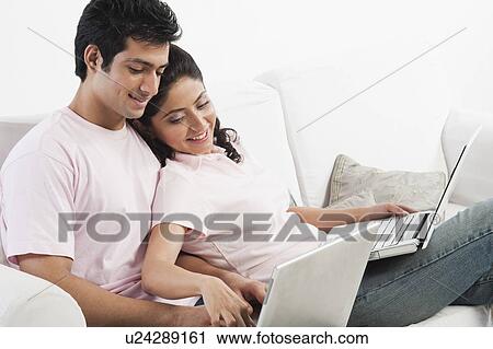 Couple working on laptops on a couch View Large Photo Image Stock Image - Couple working on laptops on a couch. Fotosearch