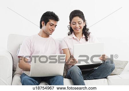 Couple working on laptops on a couch View Large Photo Image Stock Photo - Couple working on laptops on a couch. Fotosearch