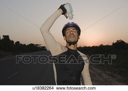 Cyclist pouring water over himself View Large Photo Image Picture - Cyclist pouring water over himself. Fotosearch