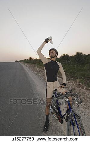 Cyclist pouring water over himself View Large Photo Image Stock Photo - Cyclist pouring water over himself. Fotosearch