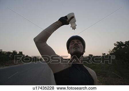Cyclist pouring water over himself View Large Photo Image Stock Photo - Cyclist pouring water over himself. Fotosearch