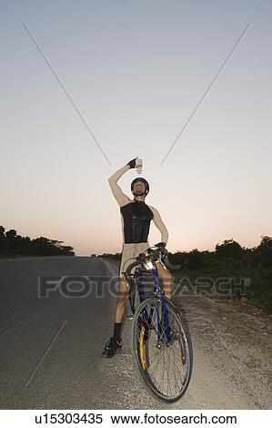 Cyclist pouring water over himself View Large Photo Image Stock Photography - Cyclist pouring water over himself. Fotosearch