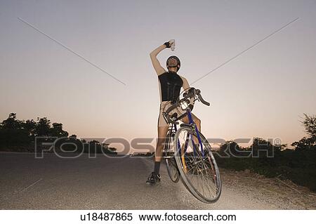 Stock Photography - Cyclist pouring water over himself. Fotosearch
