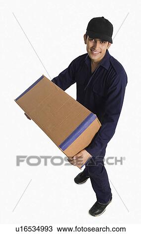 Delivery man holding a cardboard box View Large Photo Image Stock Image - Delivery man holding a cardboard box. Fotosearch