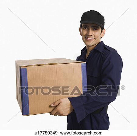 Delivery man holding a cardboard box View Large Photo Image Stock Photo - Delivery man holding a cardboard box. Fotosearch