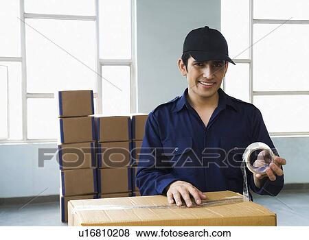 Delivery man packing cardboard box and smiling View Large Photo Image Stock Photo - Delivery man packing cardboard box and smiling. Fotosearch