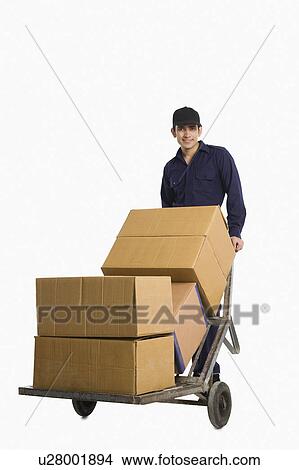 Delivery man pushing cardboard boxes on a hand truck View Large Photo Image Picture - Delivery man pushing cardboard boxes on a hand truck. Fotosearch