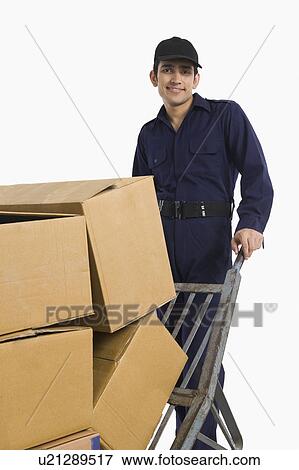 Stock Photo - Delivery man pushing cardboard boxes on a hand truck. Fotosearch