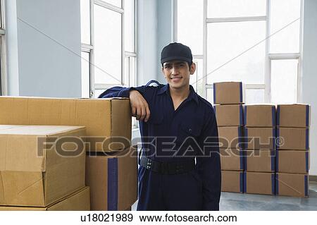 Delivery man with cardboard boxes in a warehouse View Large Photo Image Stock Photo - Delivery man with cardboard boxes in a warehouse. Fotosearch