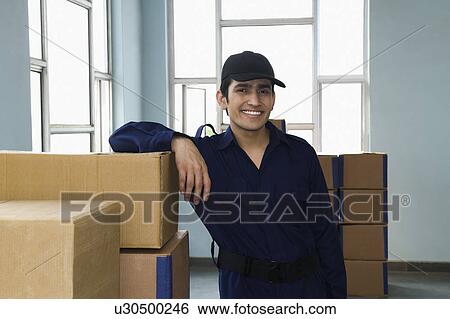 Delivery man with cardboard boxes in a warehouse View Large Photo Image Stock Photograph - Delivery man with cardboard boxes in a warehouse. Fotosearch