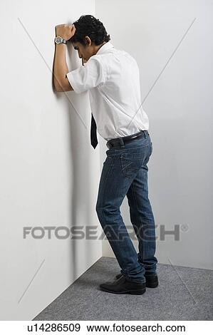 Stock Photo - Disappointed man leaning head against wall. Fotosearch