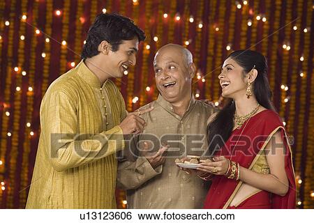Stock Photograph - Family at Diwali occasion smiling and holding a plate full of sweets. Fotosearch