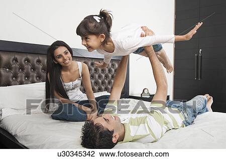 Stock Image - Family enjoying in a bedroom. Fotosearch