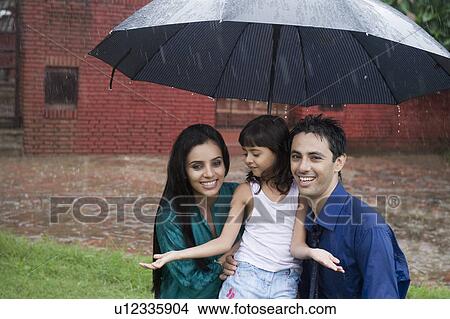 Picture - Family enjoying in rain in a park. Fotosearch