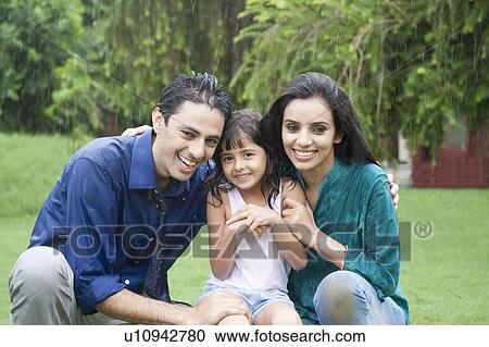 Stock Image - Family enjoying in rain in a park. Fotosearch