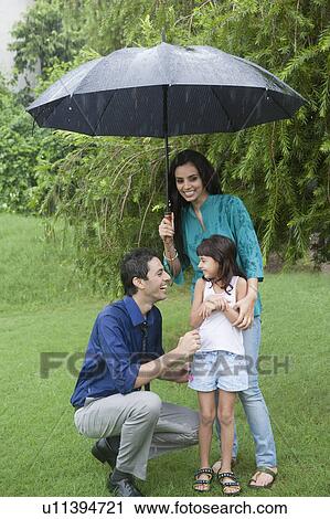 Stock Image - Family enjoying in rain in a park. Fotosearch