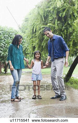 Stock Image - Family enjoying in rain in a park. Fotosearch
