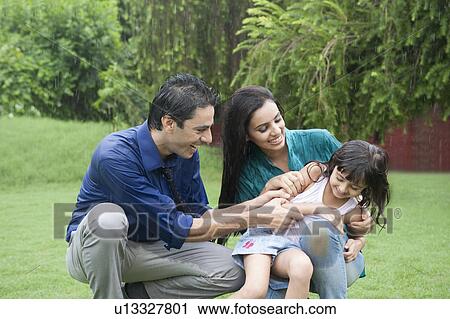 Stock Image - Family enjoying in rain in a park. Fotosearch