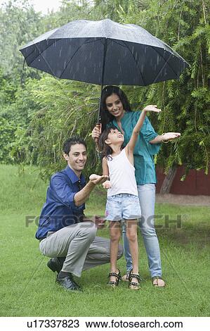 Stock Image - Family enjoying in rain in a park. Fotosearch