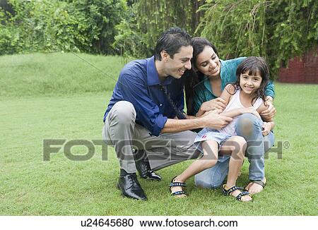 Stock Image - Family enjoying in rain in a park. Fotosearch