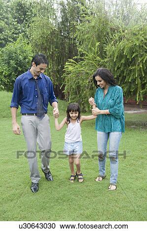 Stock Image - Family enjoying in rain in a park. Fotosearch