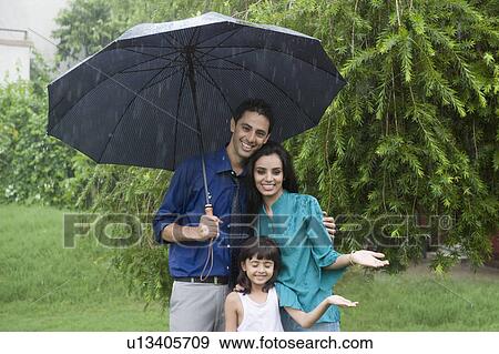 Stock Photo - Family enjoying in rain in a park. Fotosearch