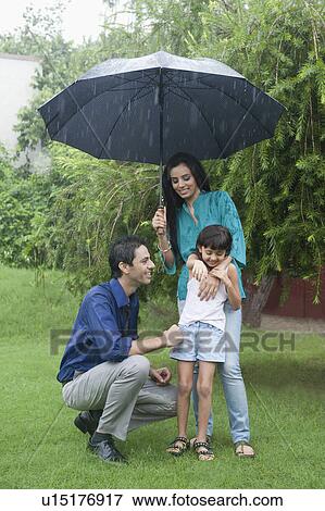 Stock Photo - Family enjoying in rain in a park. Fotosearch