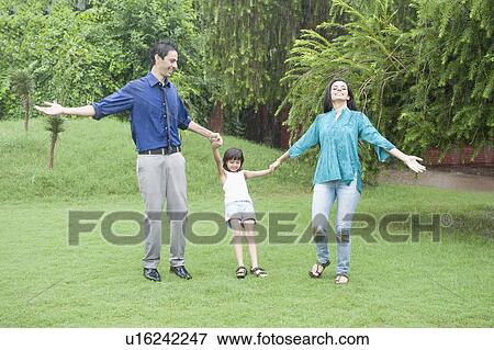 Stock Photo - Family enjoying in rain in a park. Fotosearch