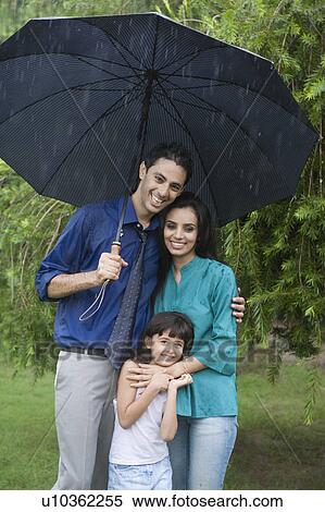 Stock Photography - Family enjoying in rain in a park. Fotosearch