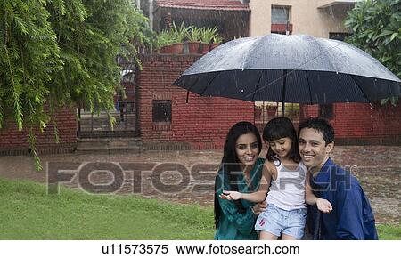 Stock Photography - Family enjoying in rain in a park. Fotosearch