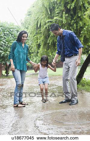 Stock Photography - Family enjoying in rain in a park. Fotosearch