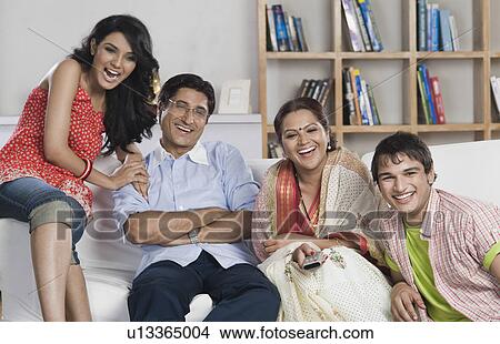 Family sitting on a couch watching TV together View Large Photo Image Picture - Family sitting on a couch watching TV together. Fotosearch