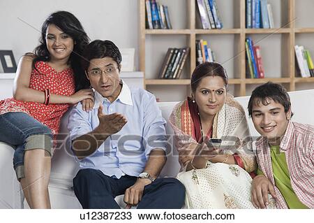 Stock Image - Family sitting on a couch watching TV together. Fotosearch